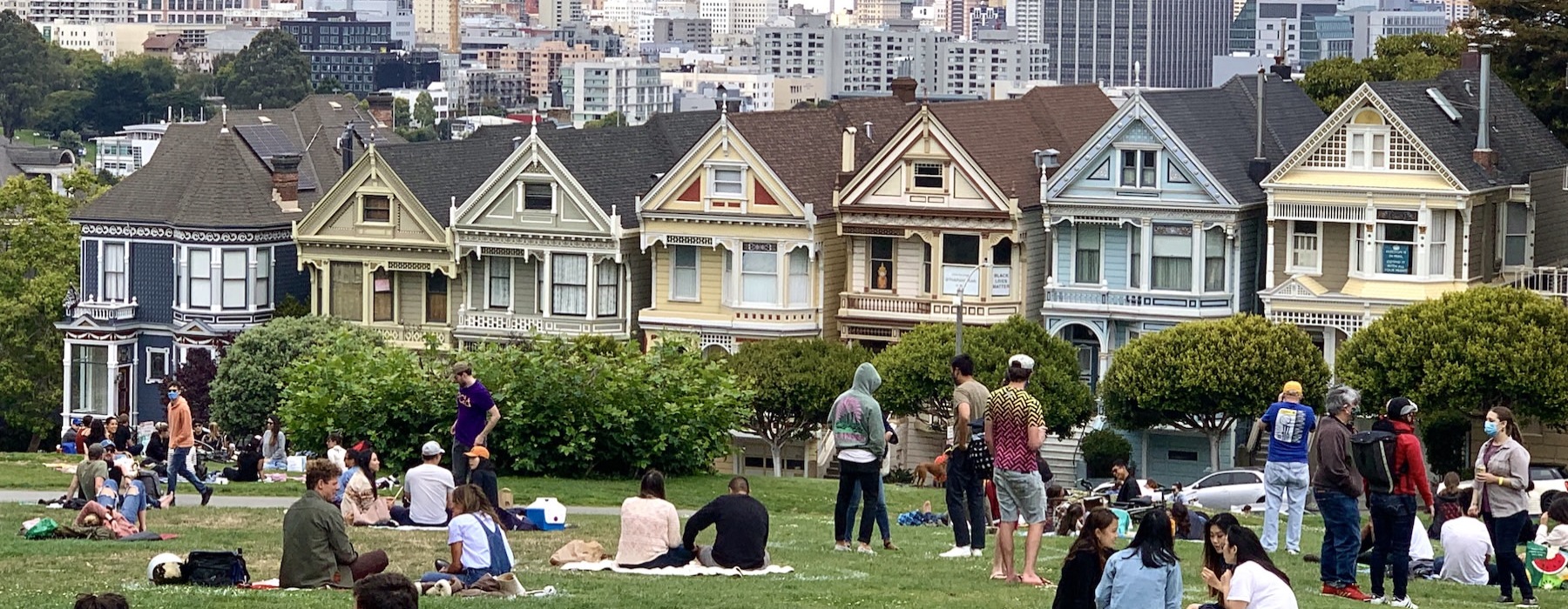 a group of people sitting on the grass in front of a city